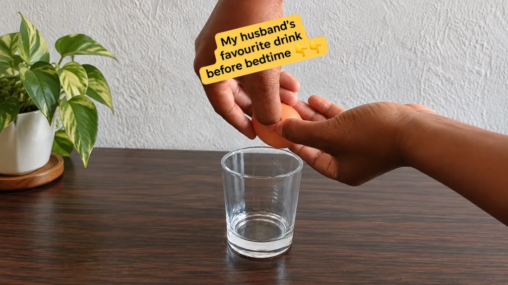 A close-up of hands cracking an egg over a clear glass on a dark wooden table with a yellow text overlay My husband s fa