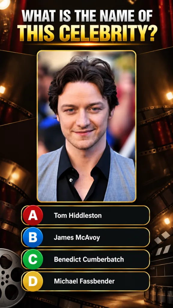 A headshot of actor James McAvoy looking directly at the camera with a subtle smile wearing a black shirt and a light gr