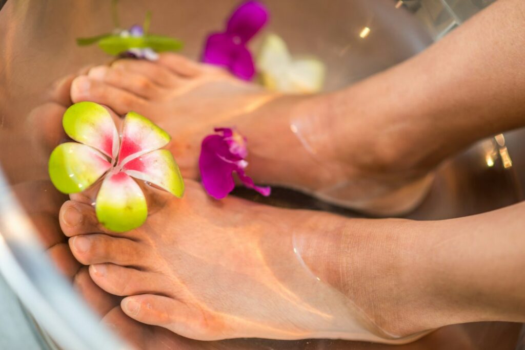 Various natural ingredients for foot soaks laid out on a rustic wooden table Epsom salts in a bowl a small bottle of lav