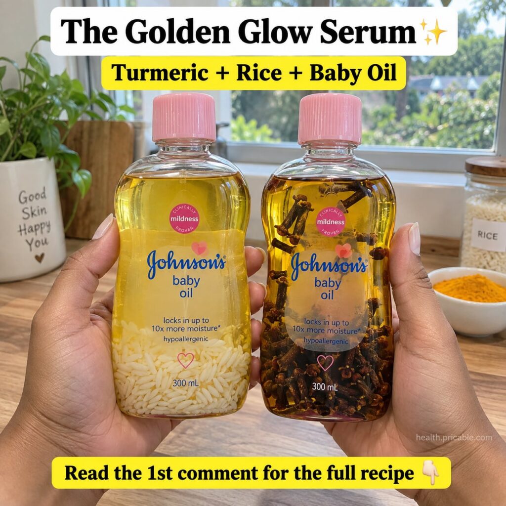 A close-up of a glass bottle containing a light yellow oil serum with rice grains and whole cloves visible inside The ba