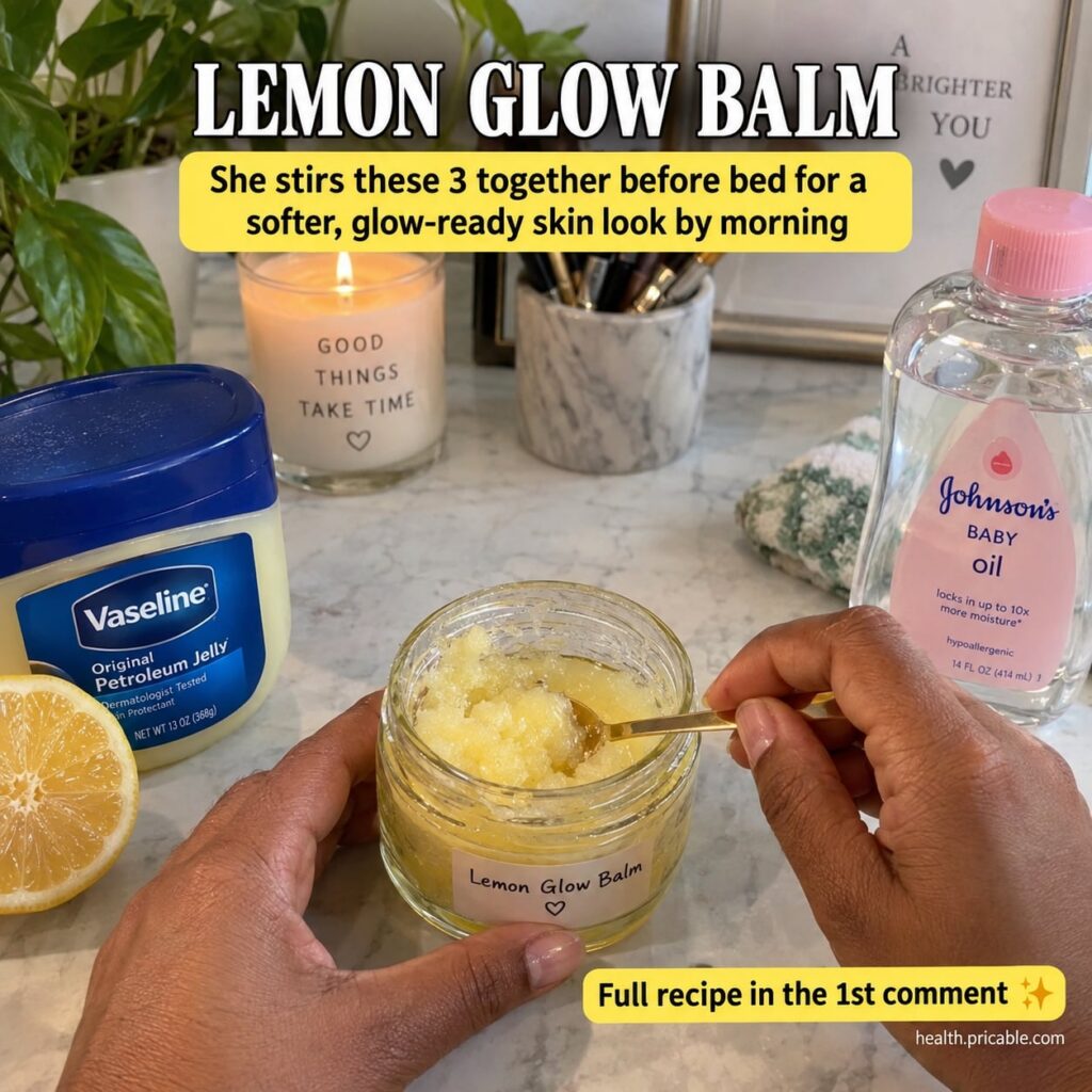 A small glass jar of homemade yellow balm with a sliced lemon a bottle of baby oil and a tub of Vaseline around it on a 