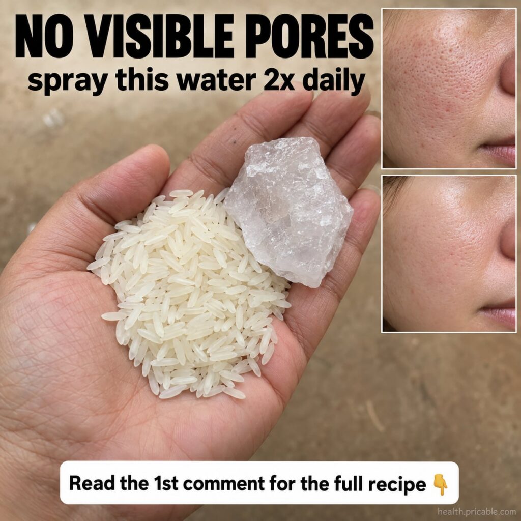 A clear spray bottle filled with cloudy rice water with some white rice grains scattered next to it on a light backgroun