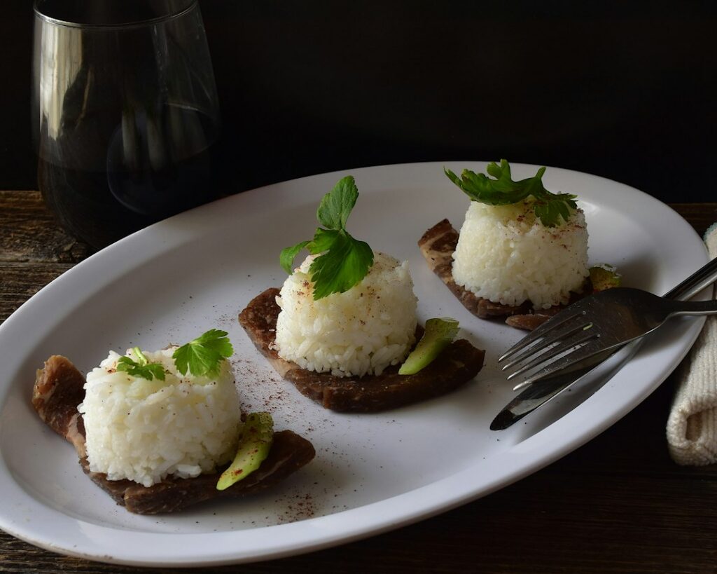 Two rice cakes spread with creamy hummus and topped with thinly sliced cucumbers and a sprinkle of everything bagel seas