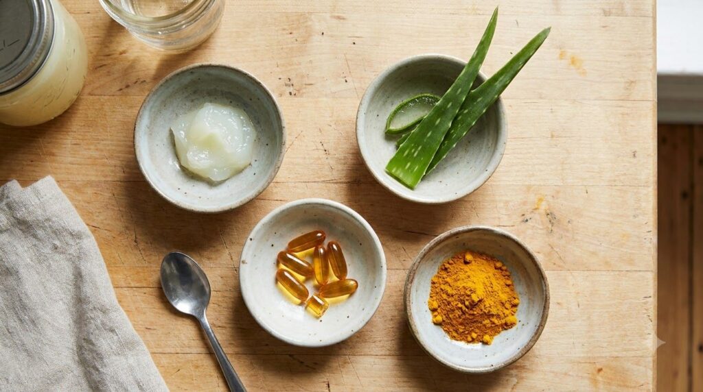 Small bowls of ingredients like Vaseline aloe vera gel a vitamin E capsule and turmeric powder laid out neatly for a DIY