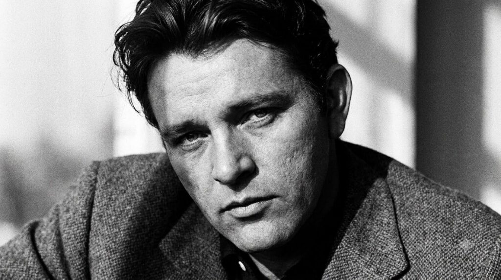 A black and white portrait of a young Richard Burton looking intense and charismatic perhaps from the era of My Cousin R