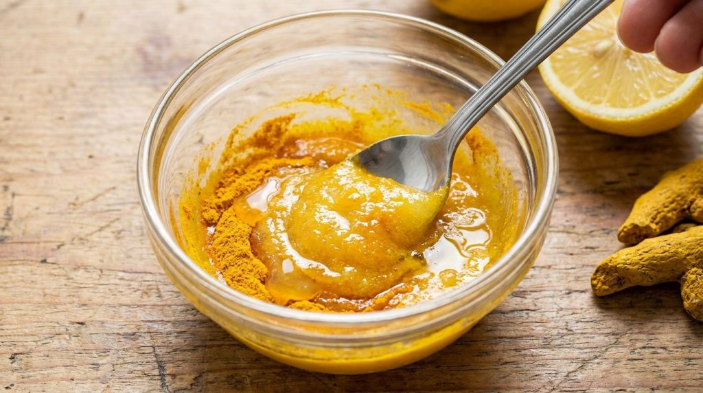 A small bowl with Vaseline turmeric powder and lemon juice being mixed into a smooth yellow paste