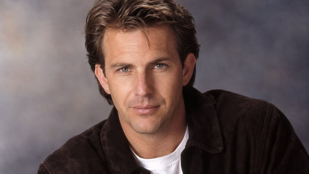 A real publicity photo of Kevin Costner from his younger years showcasing his classic leading man look possibly from the