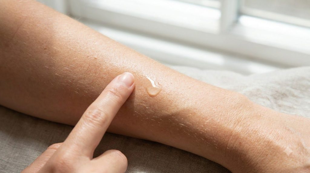 A close-up of a hand performing a patch test on the inner arm with a small drop of oil highlighting a safe skincare prac