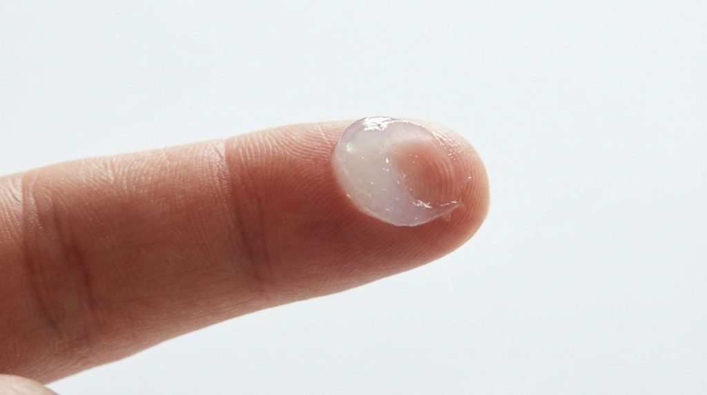 A small scoop of Vaseline Petroleum Jelly on a fingertip showing its translucent protective texture