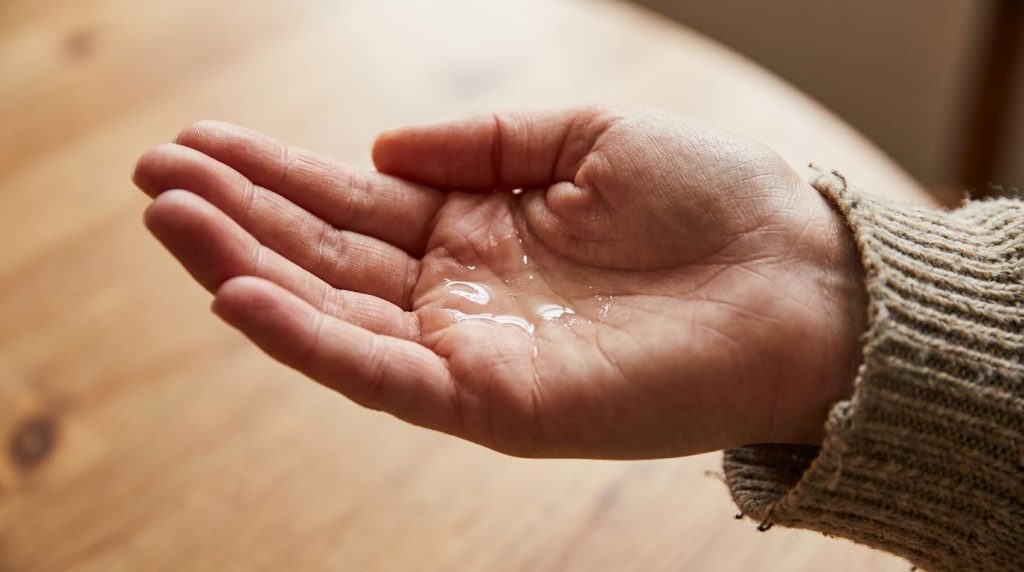 A close-up shot of a woman s hand mixing Vaseline baby oil and vitamin E oil in her palm ready to be applied to the face