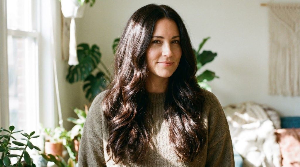 A woman with visibly healthy shiny and thick-looking hair after using a natural hair remedy like aloe vera oil smiling g