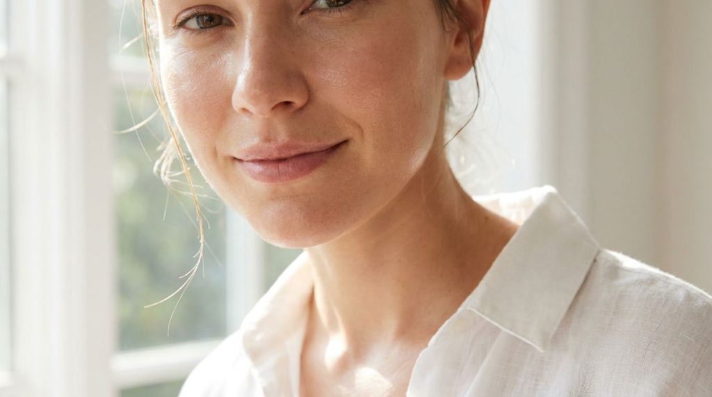 A close-up of a person s glowing well-hydrated face in the morning light showing smooth and plump skin representing the 