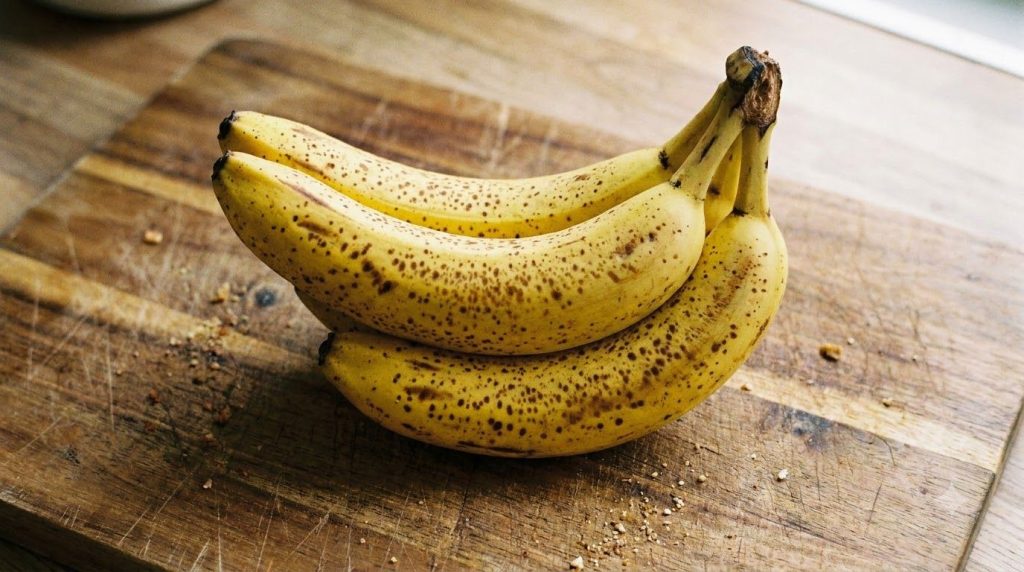 A cluster of ripe yellow bananas with brown spots ready for mashing