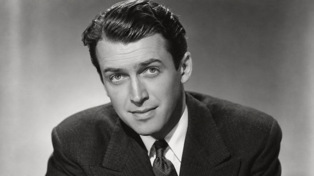 A black and white photograph of a young James Stewart perhaps in the late 1930s looking earnest and slightly shy in a cl