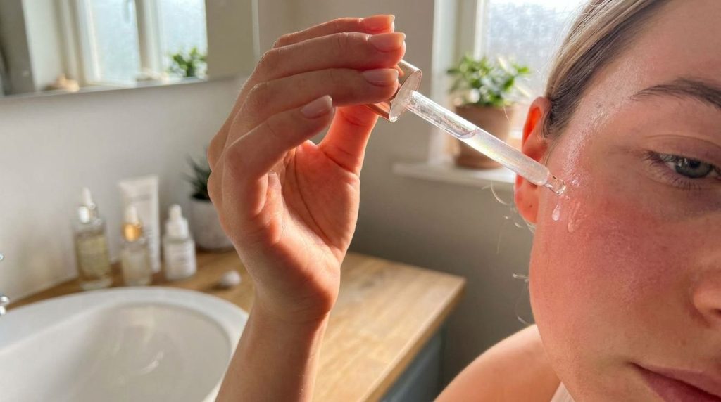 A person s hand gently applying a few drops of the DIY oil blend to their clean face focusing on the cheek area