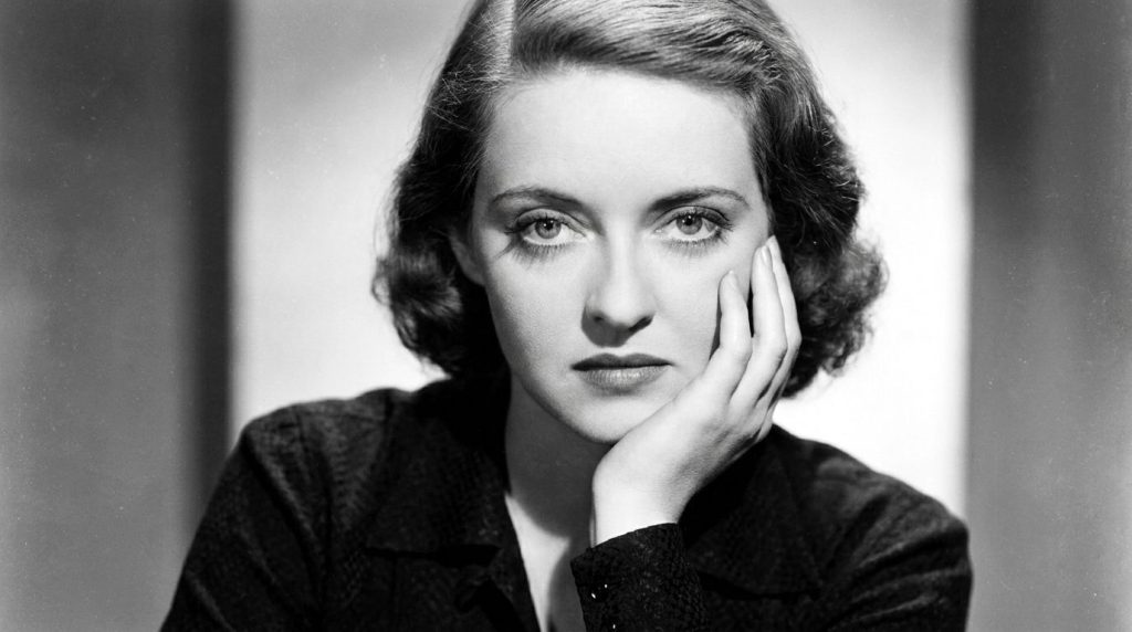 A real archival publicity photo of a young Bette Davis from the 1930s or 1940s showcasing her intense eyes and classic H