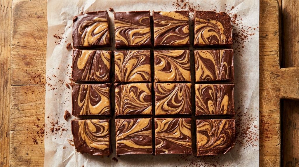 Smooth swirled chocolate and peanut butter fudge cut into perfect squares on parchment paper