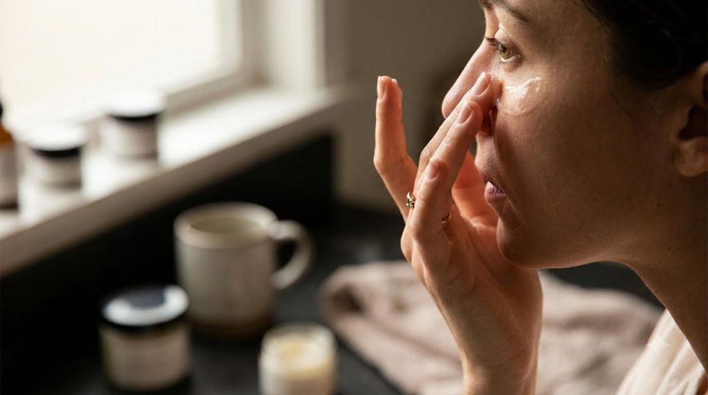 A woman gently applying a small amount of the Vaseline and Almond Oil Line Softener to the delicate skin under her eyes 