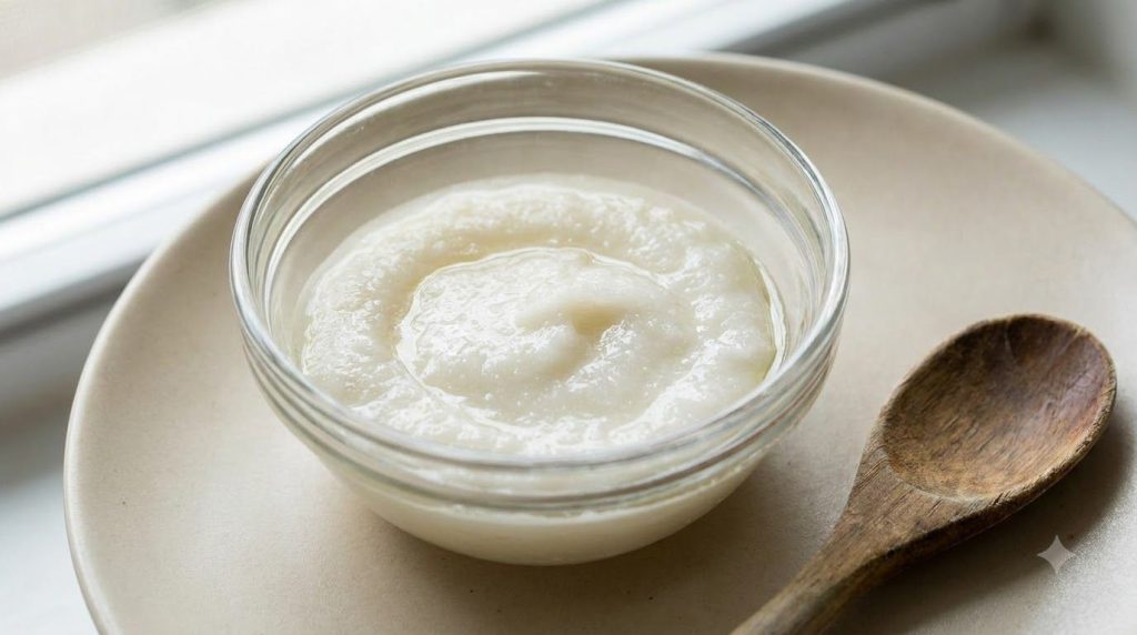 A close-up of a smooth white paste made from crushed aspirin and baby oil in a small glass bowl