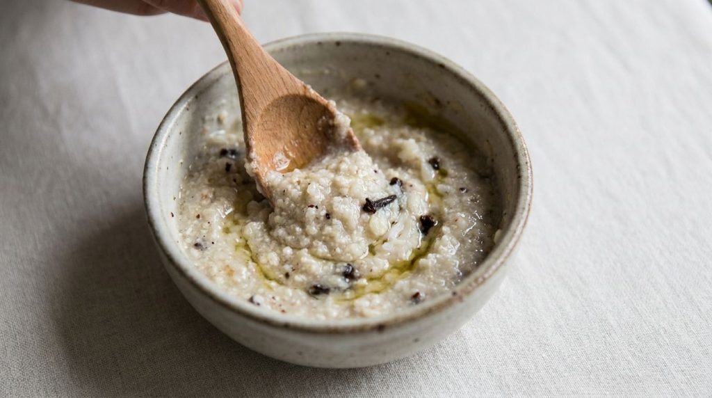 A close-up shot of a small bowl containing the mixed DIY glass skin paste with a spoon stirring the creamy mixture of gr