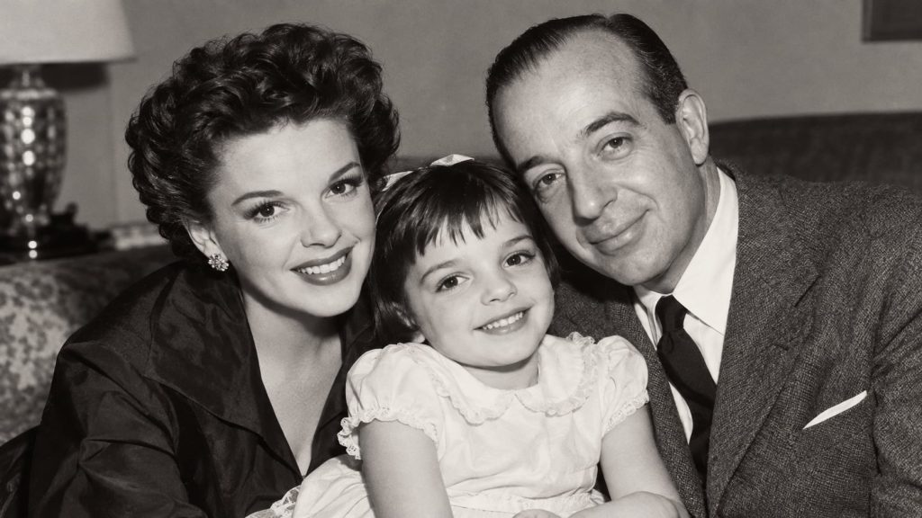 A black and white photograph of Judy Garland Vincente Minnelli and a young Liza Minnelli together possibly at an event o