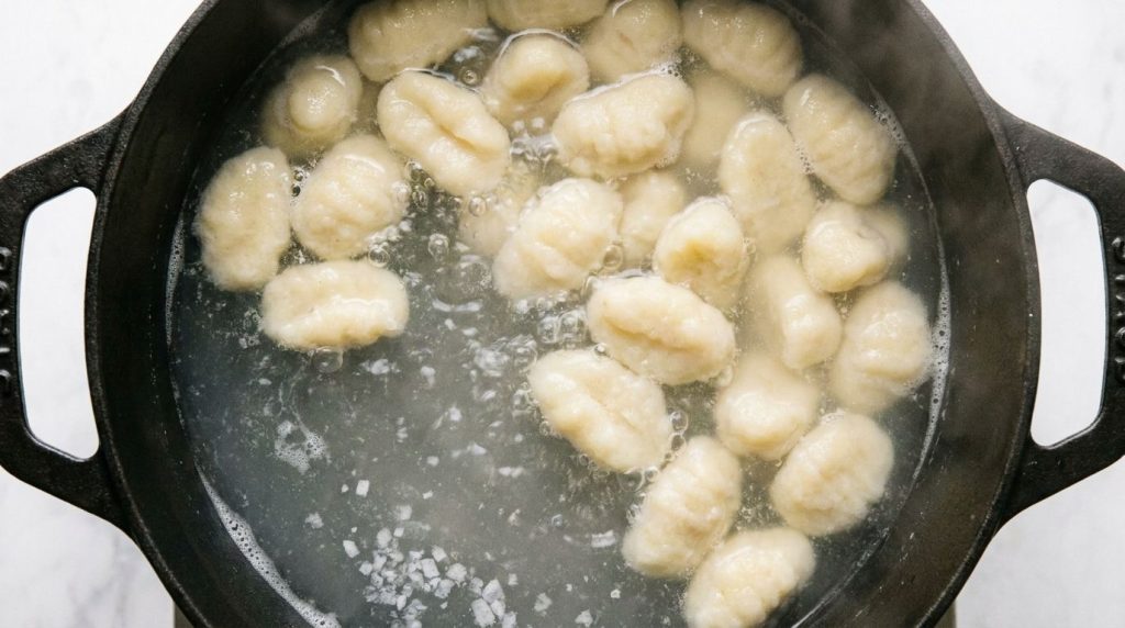 Freshly boiled gluten-free and vegan gnocchi floating on the surface of salted water in a pot