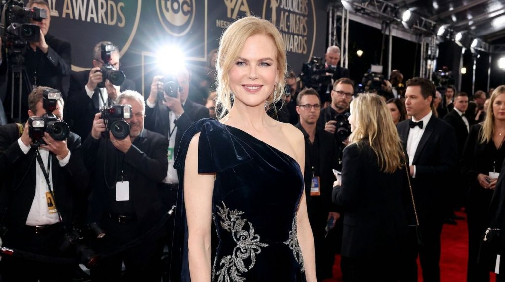 Nicole Kidman on a red carpet elegantly dressed smiling at the cameras