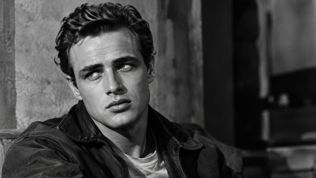 A black and white photo of a young intense classic Hollywood actor looking off-camera with a moody expression