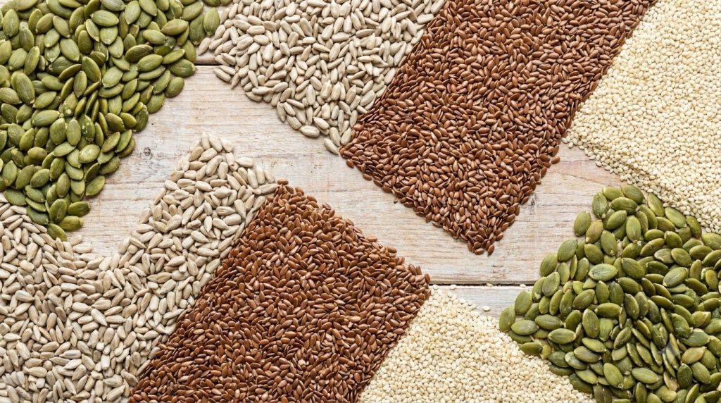Various seeds like pumpkin sunflower flax and sesame laid out on a clean counter ready for mixing