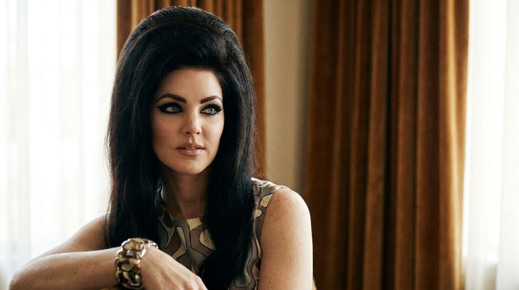 Priscilla Presley in the 1960s with her signature beehive hair and dramatic eye makeup exuding classic Hollywood glamour
