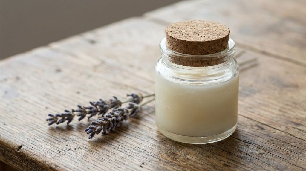 Close-up of a small glass jar filled with a creamy off-white Vaseline-based gel ready for use with natural light