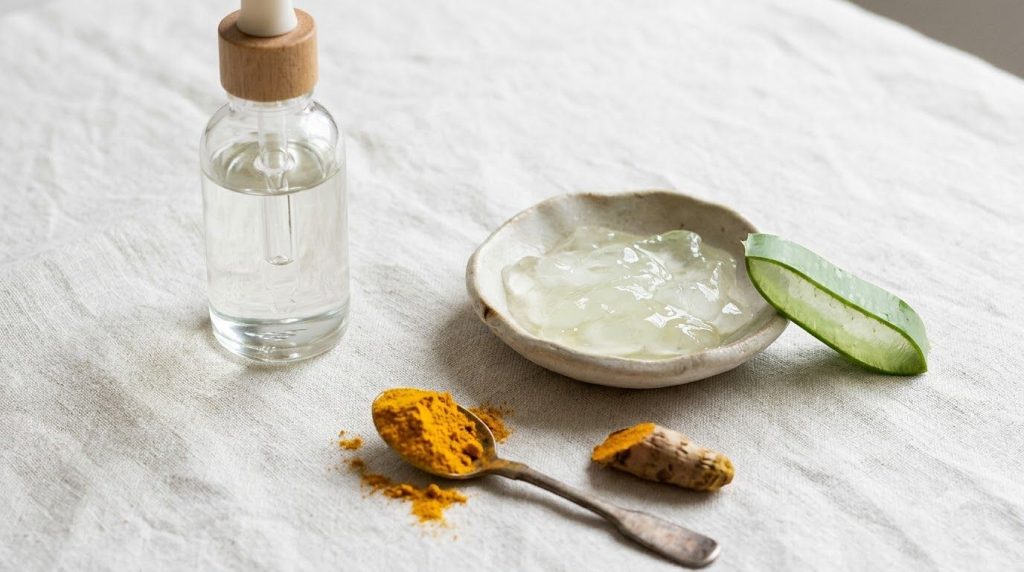 Ingredients for Soothing Turmeric Aloe Mask baby oil fresh aloe vera gel and turmeric powder in a bright clean setting