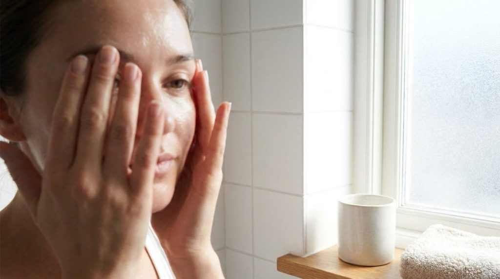 A woman s hands gently massaging her face with a soft circular motion Her skin looks fresh and moisturized after rinsing