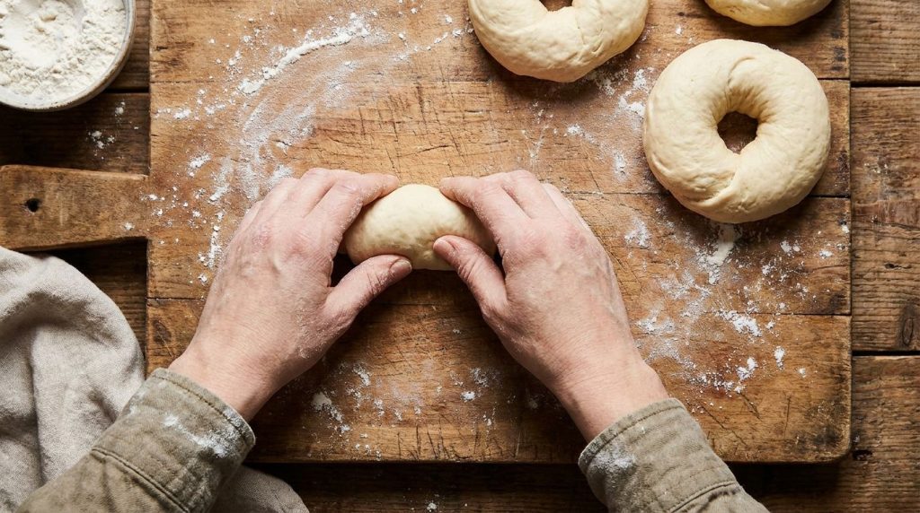 Hands shaping bagel dough