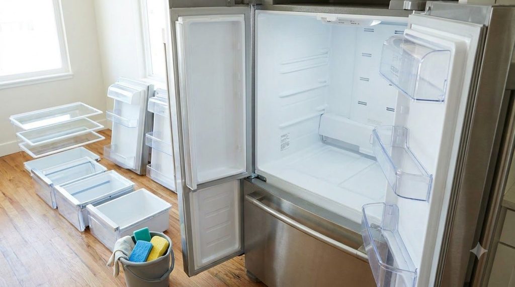 An open empty refrigerator with all shelves and drawers removed ready for cleaning