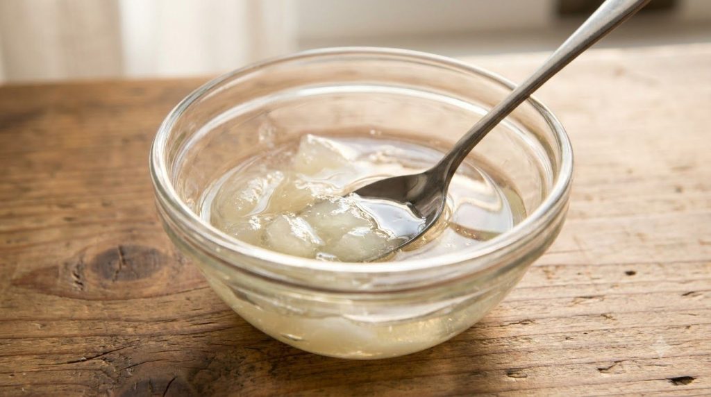 Close-up of a small glass bowl with melted Vaseline and baby oil ready for other ingredients to be added for a DIY beaut