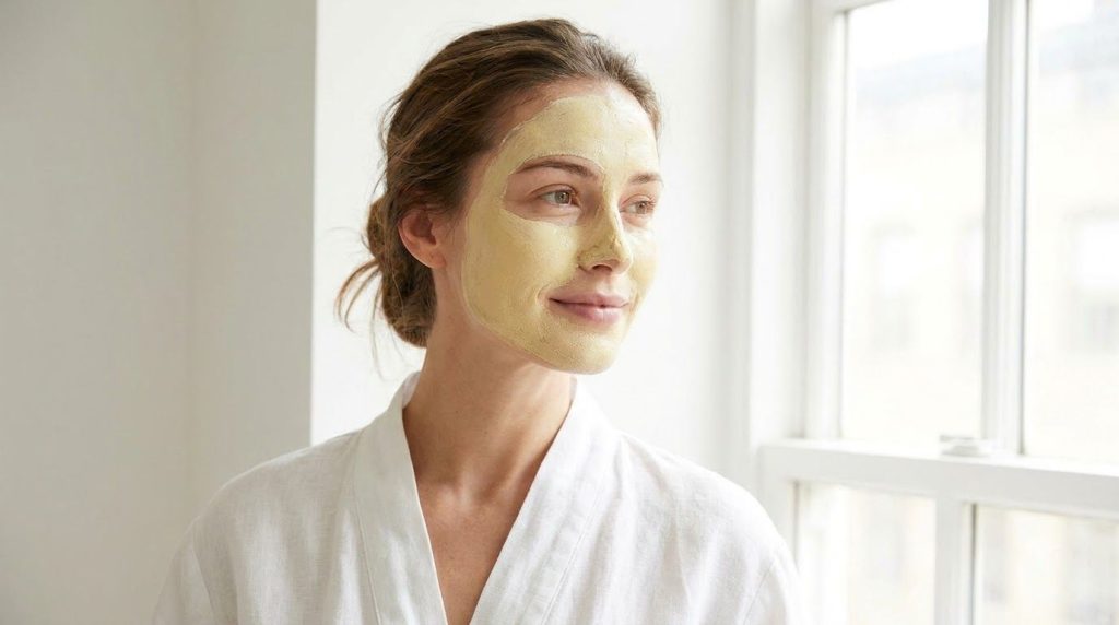 A person s face with a thin layer of the yellow mask applied looking relaxed and radiant perhaps with a soft glow effect
