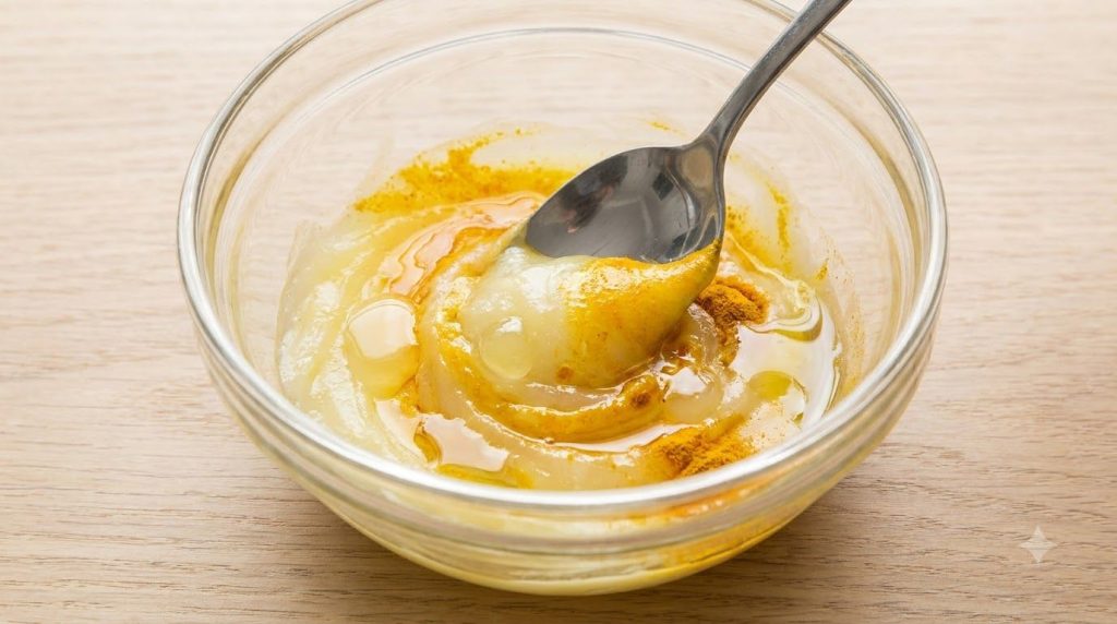 A close-up of the ingredients petroleum jelly turmeric lemon juice baby oil being mixed together in a clear glass bowl t