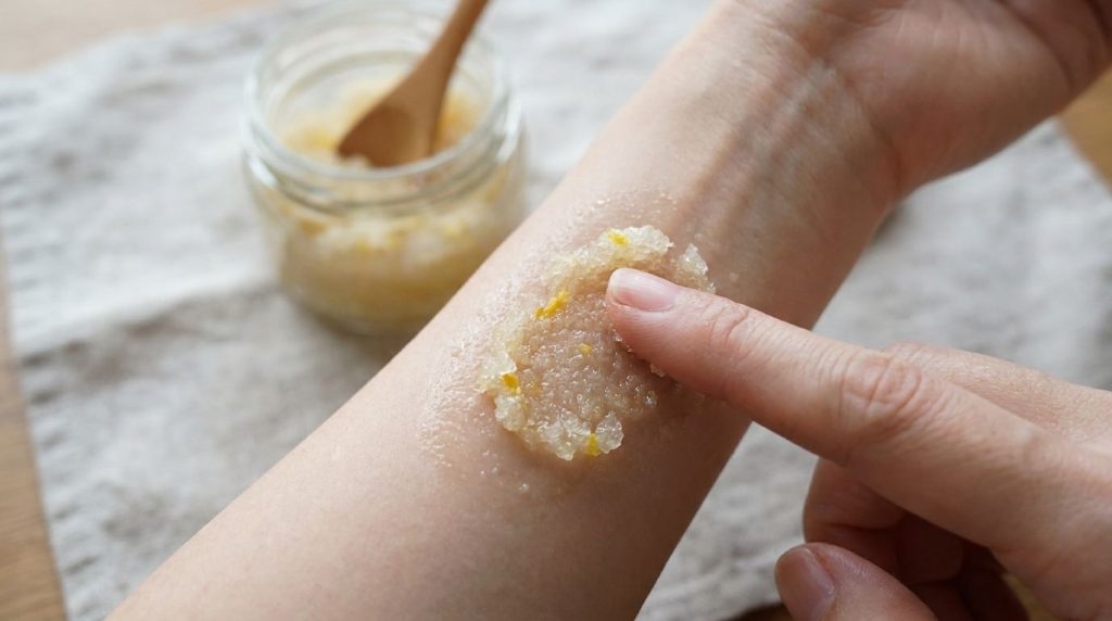 A close-up of a hand testing a small amount of the sugar and lemon scrub on the inner forearm