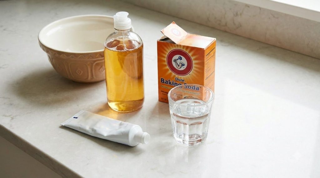 Ingredients for cleaning sneakers laid out a tube of white toothpaste a bottle of dish soap a box of baking soda and a g