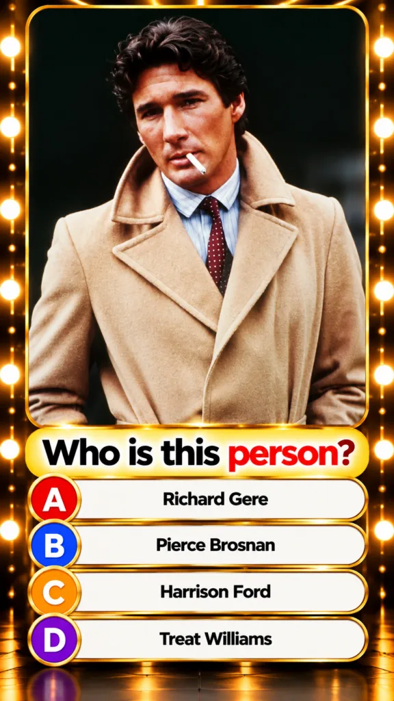 Young Richard Gere in a camel trench coat pinstriped shirt and burgundy tie holding a cigarette with a confident express