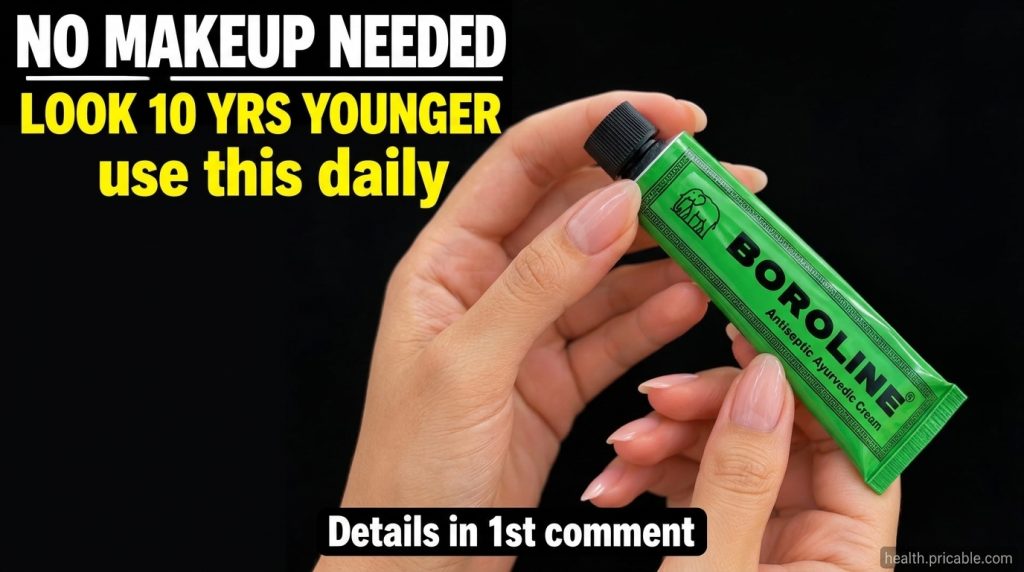 A hand holding a green tube of Boroline ointment against a soft glowing background
