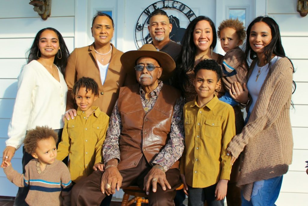 Promotional still from The Cosby Show featuring Bill Cosby as Cliff Huxtable interacting with his on-screen family in a