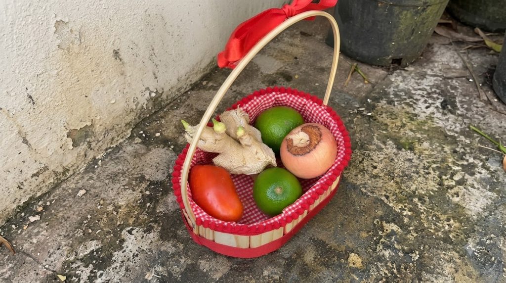 A rustic wicker basket with red liner and trim filled with two limes a Roma tomato ginger root and a light pink round fr