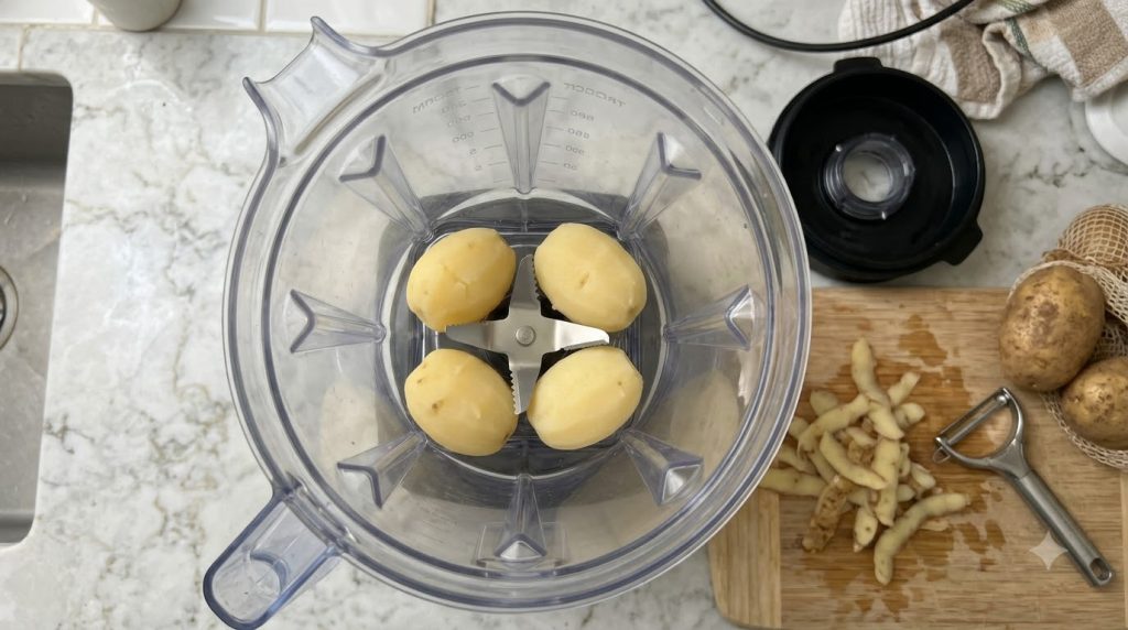 Cuatro patatas cocidas y peladas dentro de una licuadora listas para ser procesadas